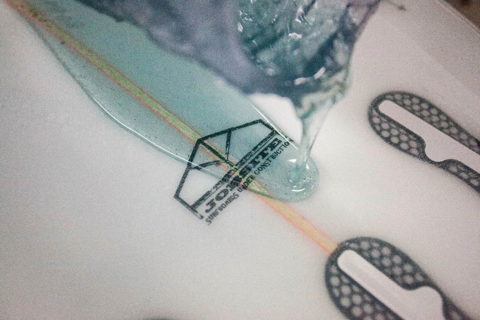 Close-up of surfboard glassing process, resin application